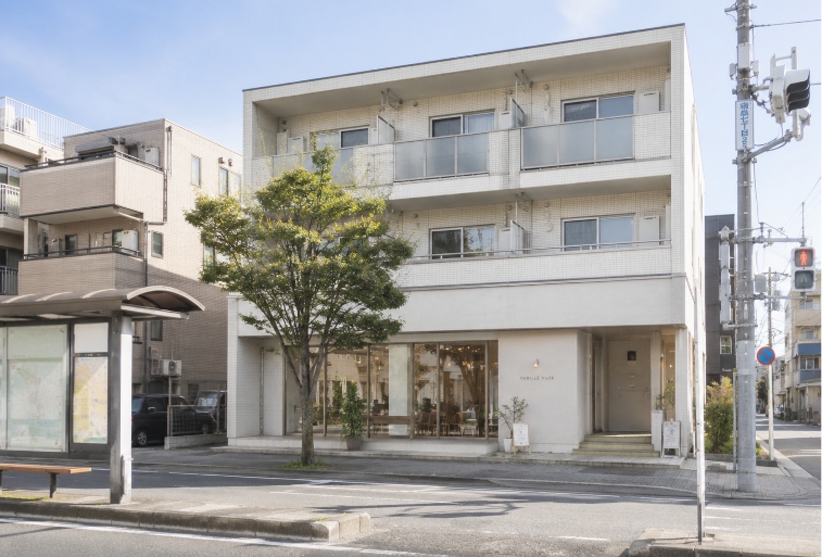 バス停を降りると、右斜め向かいに3階建ての山中マンションがあります。FAMILLE HAIRは1階・106号室です。